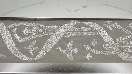 a textile work with scissor cut pattern depicting humans and birds flying